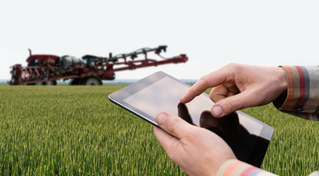 Farmer controls sprayer with a tablet. Smart farming and precision agriculture noe agtech revolution in practice