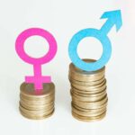 Female and male gender symbol on coins. Gender wage gap.